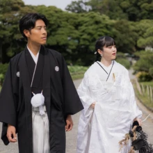 三溪園の豊かな緑の中をゆっくりと歩くふたり。白無垢と黒紋付が美しく映える、自然体の和装フォトウェディング|縁グラフィの姉妹ブランドLuca 横浜・三溪園の緑豊かな日本庭園を歩く、白無垢姿の花嫁と黒紋付姿の新郎の和装ウェディングフォト