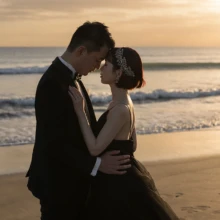 由比ヶ浜の夕日に包まれて寄り添う、ブラックドレスが映えるロマンチックなウェディングフォト|縁グラフィの姉妹ブランドLuca 由比ヶ浜の夕日を背景に、黒いウェディングドレス姿の花嫁とタキシード姿の新郎が寄り添うウェディングフォト