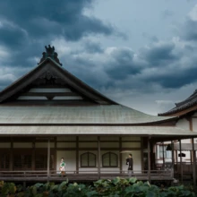 鎌倉 和装 T様・U様 2020.09.29 曇り空の下に建つ光明寺の大きな伽藍と、長い回廊に並ぶ和装の新郎新婦を遠景から捉えた構図