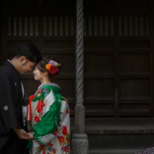 鎌倉 和装 T様・U様 2020.09.29 光明寺の山門前で手をつなぎ、額を寄せ合う色打掛の新婦と黒紋付袴の新郎の親密な瞬間