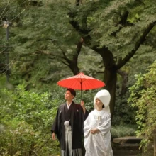 鎌倉 和装 N様N様 2020.11.02 妙本寺の参道で、赤い和傘を差す黒紋付袴姿の新郎と綿帽子と白無垢姿の新婦が並んで歩く
