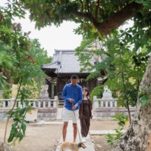 ペット・家族写真 K様 2025.10.13 鎌倉の神社で、ロングコートダックスフンドを連れた男女が大きな木の間の参道を歩く様子