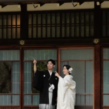 鎌倉 和装 T様・K様 2026.04.05 円覚寺の縁側で、上方を指さす黒紋付袴の新郎の腕に白無垢の新婦が手を添える和やかな姿
