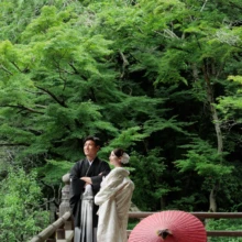 鎌倉 和装 I様・Y様 2026.07.05 初夏の新緑に囲まれた妙本寺で、赤い番傘を足元に置き寄り添う白無垢の新婦と黒紋付袴の新郎